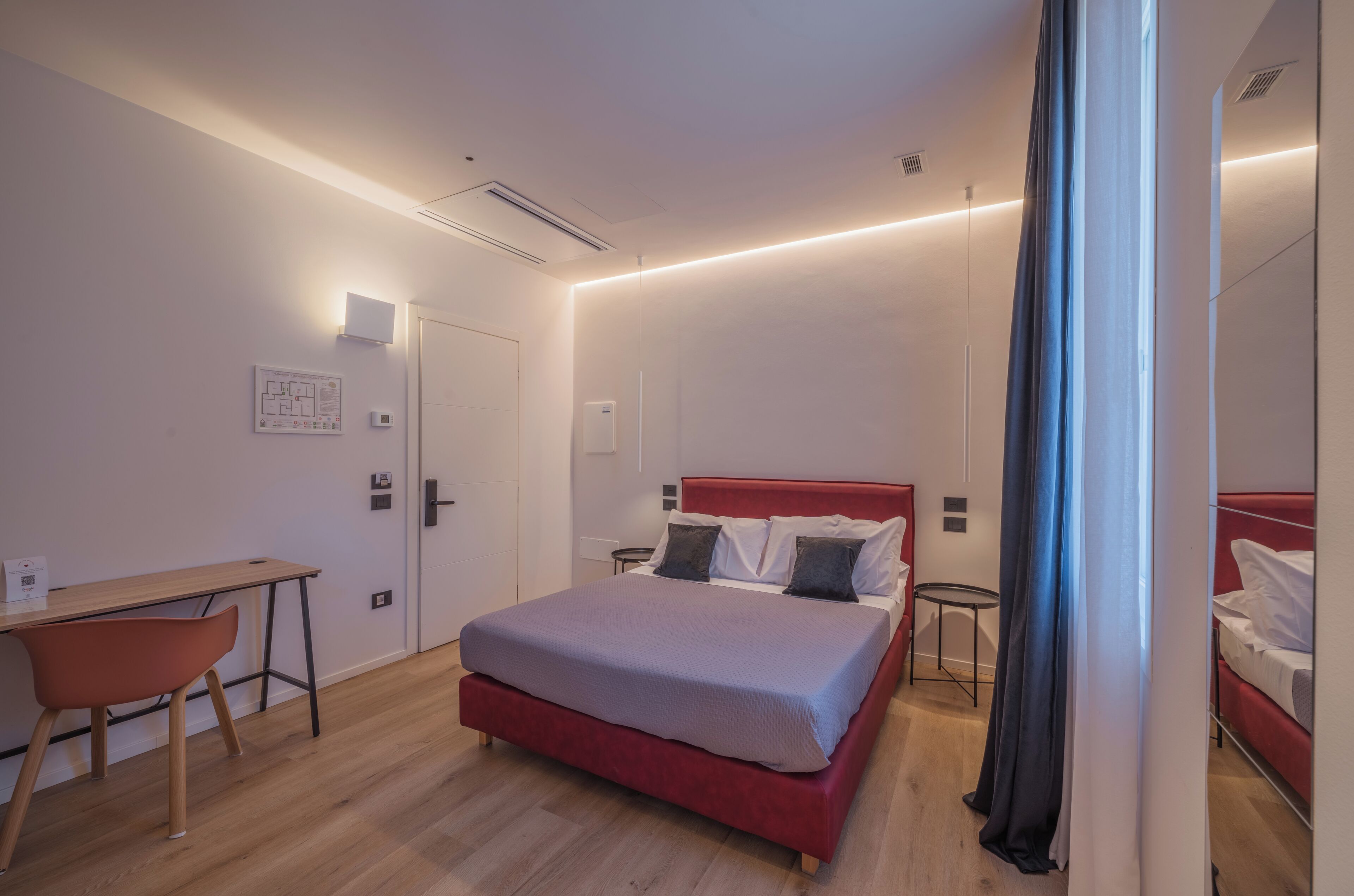 Una habitación de hotel moderna con una cama, escritorio, silla y una pequeña mesa.