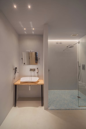 Ein Badezimmer mit Waschbecken, Spiegel, Dusche und Fliesenboden.