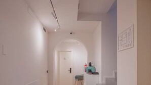 A hallway with a staircase leading to a room, a door, and a small table with a chair. - DIMORA IN PRATO (Padova)