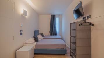 Ein Schlafzimmer mit zwei Betten, einem Fernseher, einem Kleiderschrank und einem Nachttisch.
