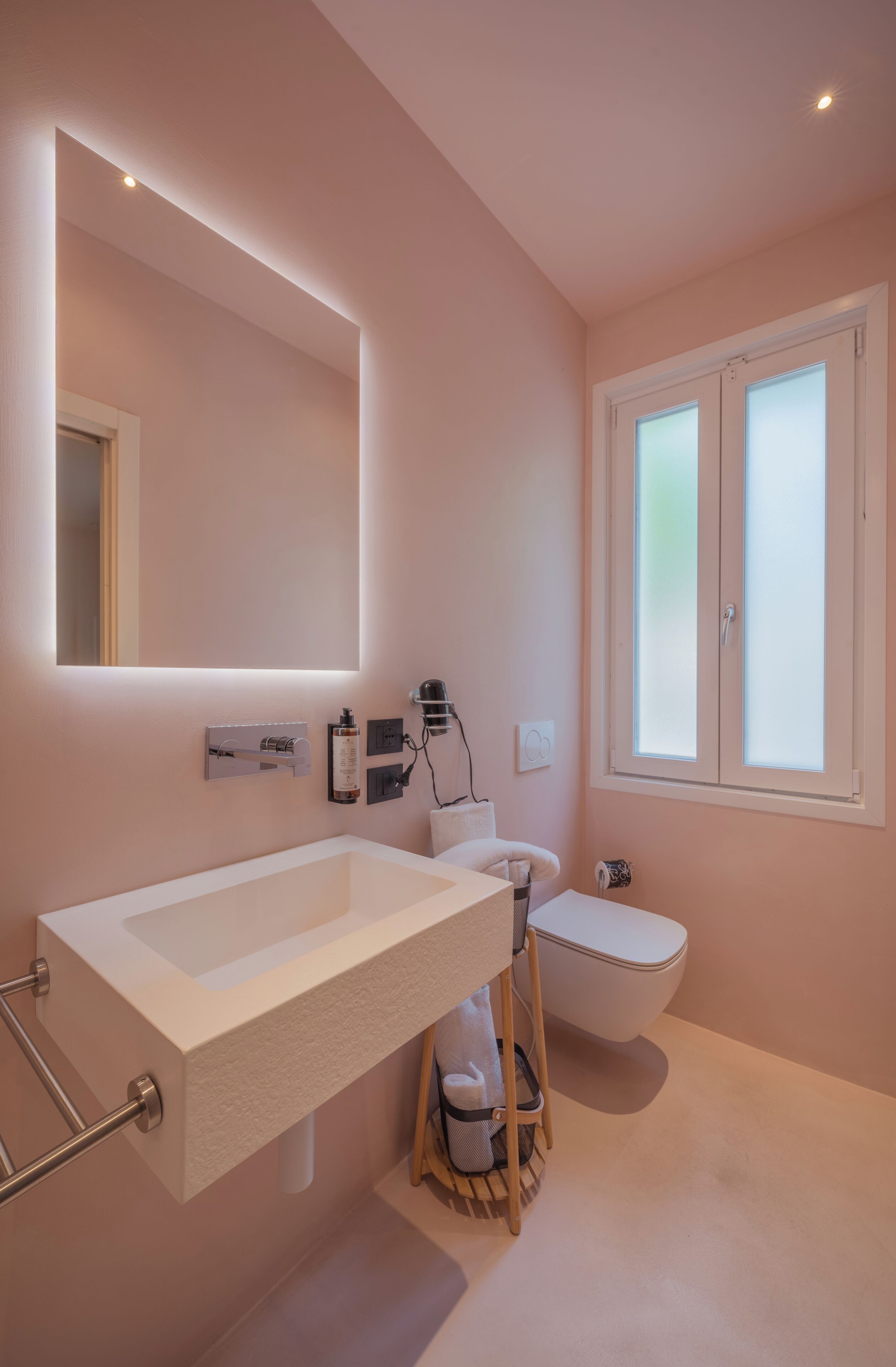 Un baño moderno con un lavamanos blanco grande, un inodoro y un espejo.