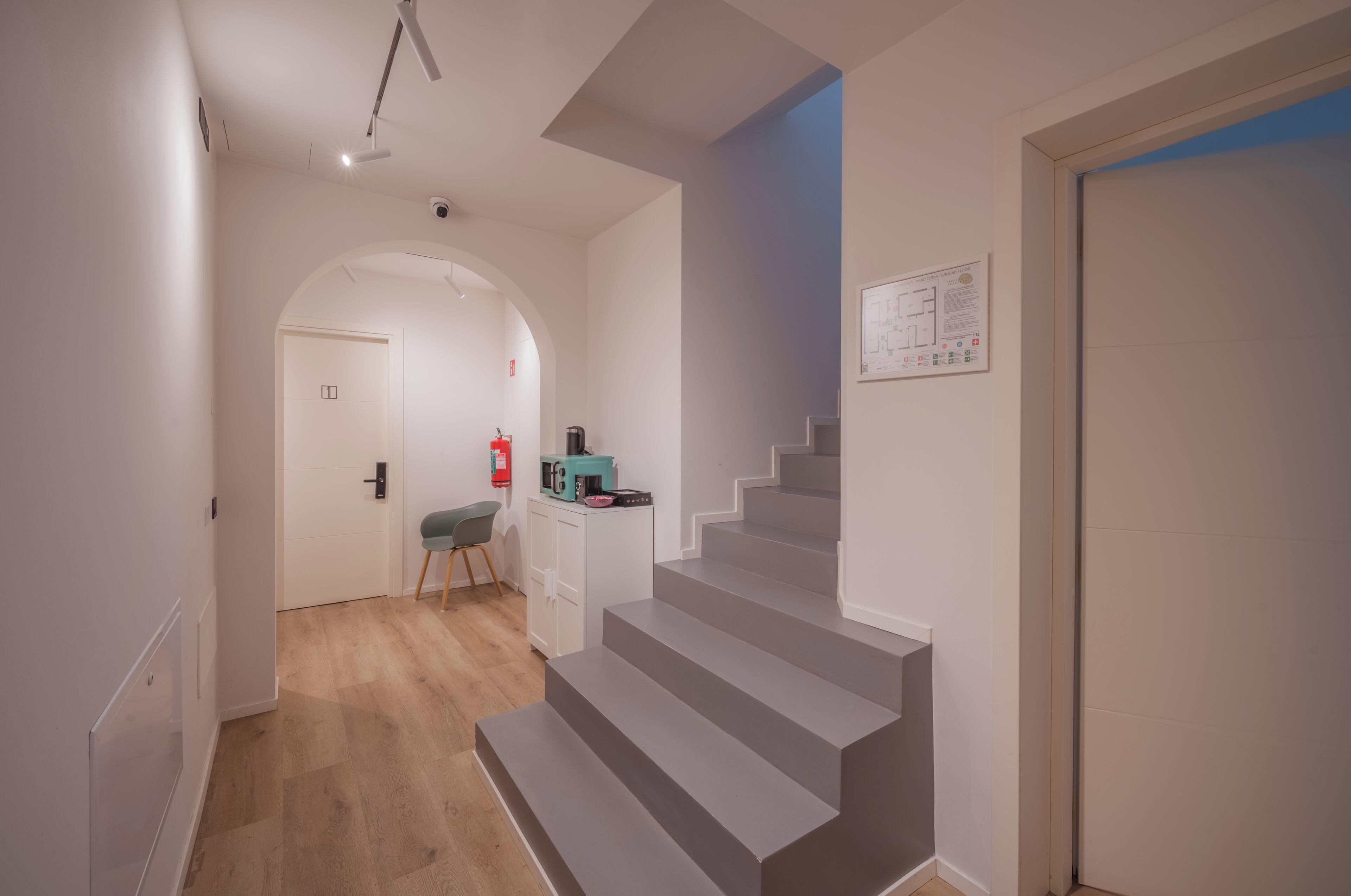 Un interior modern amb una escala, una zona de cuina i una porta amb un senyal de seguretat contra incendis.
