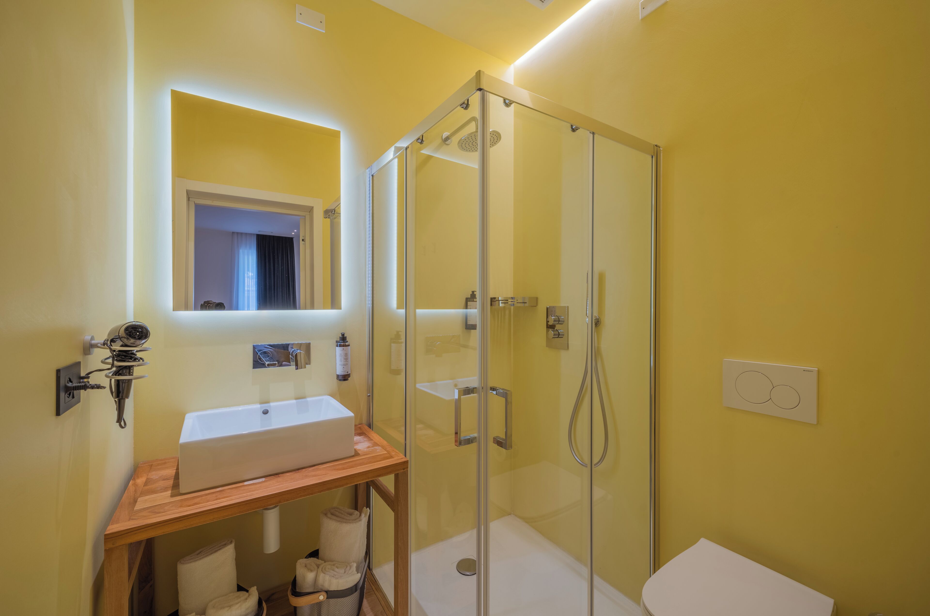 A bathroom with a glass-enclosed shower, a white sink, and a mirror above it.