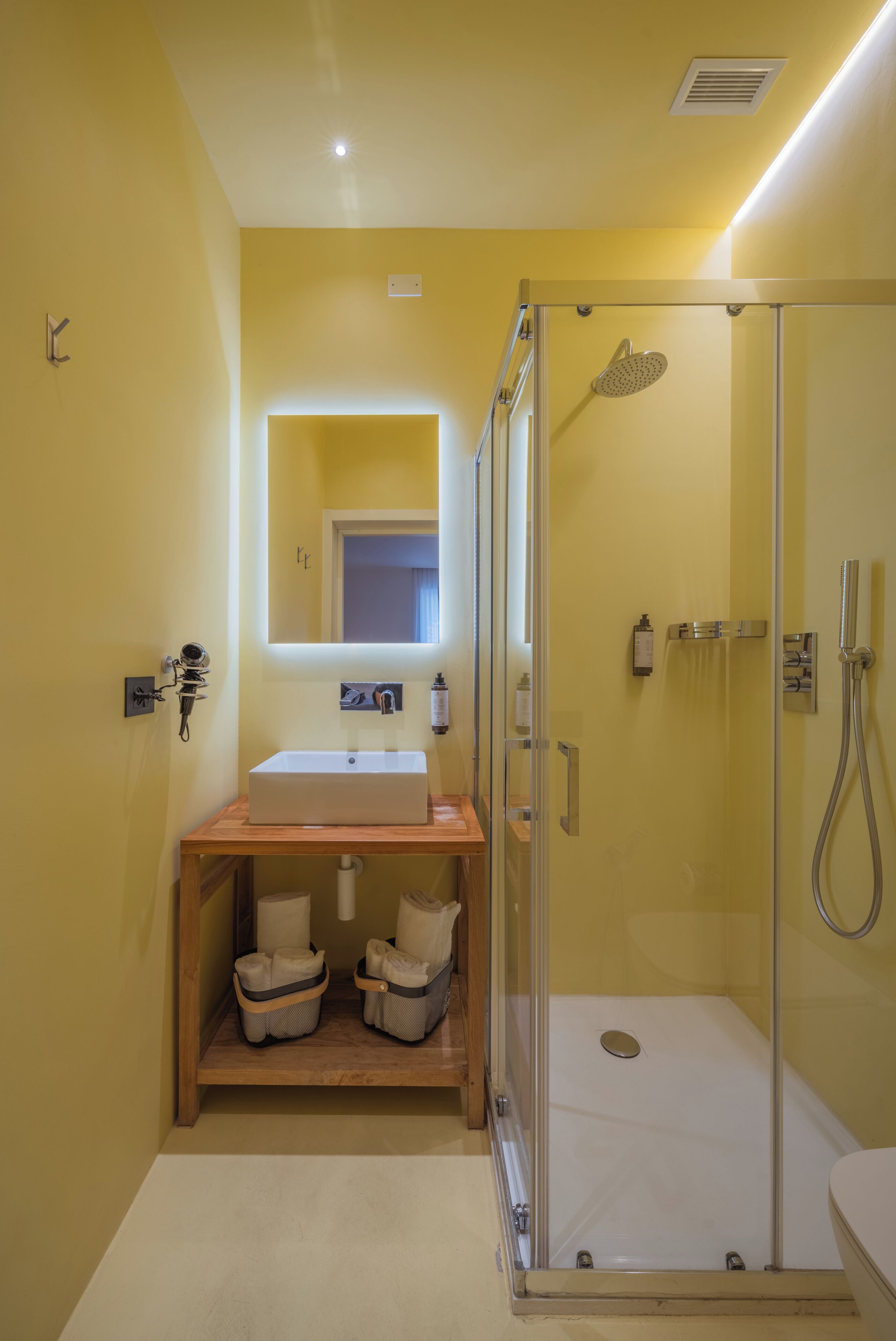 A bathroom with a glass-enclosed shower, a sink, and a mirror.
