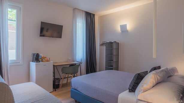 A modern hotel room with a bed, a desk with a chair, a TV, and a wardrobe. - DIMORA IN PRATO (Padova)