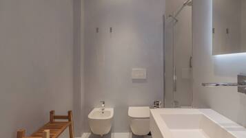 Een moderne badkamer met een groot wit wastafelmeubel, een douche en een houten handdoekhouder.