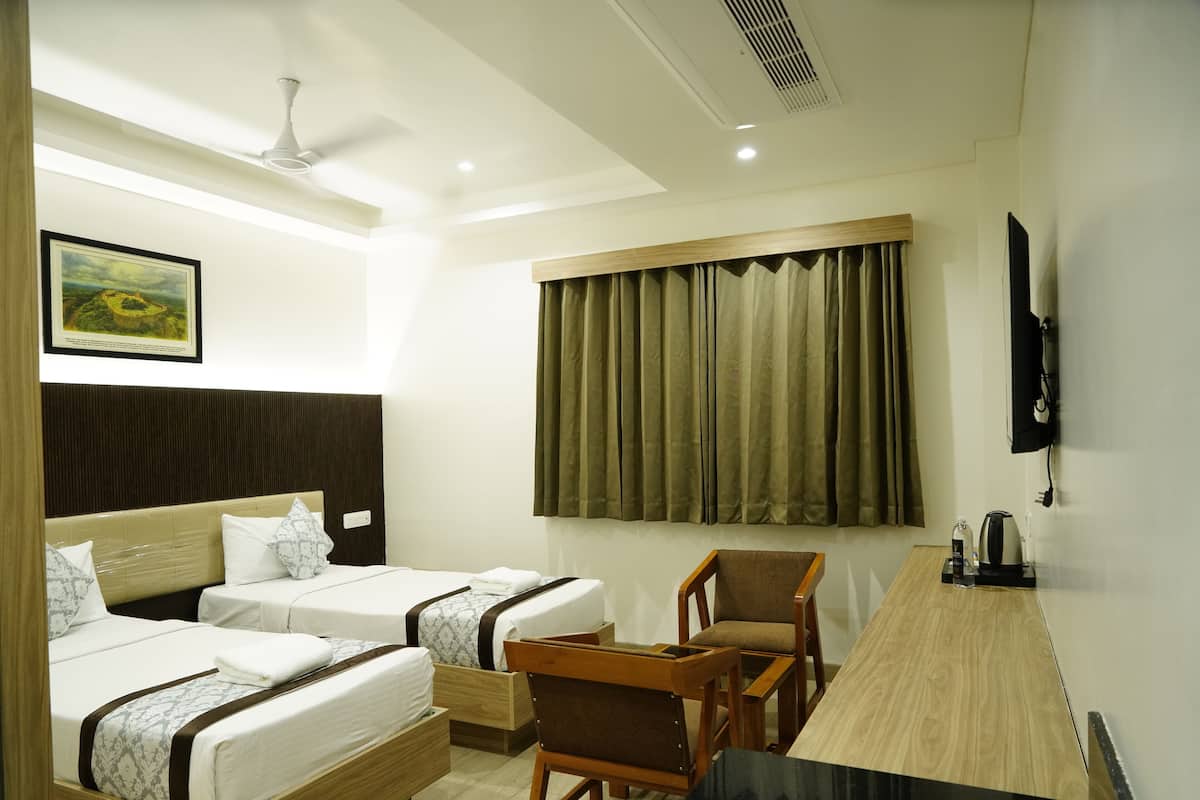 A hotel room with two beds, a desk, a chair, a television, and a window with curtains.