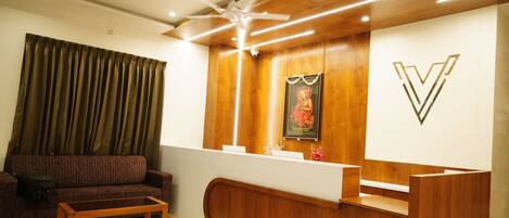 A reception area with a wooden reception desk, a ceiling fan, and a framed picture on the wall.
