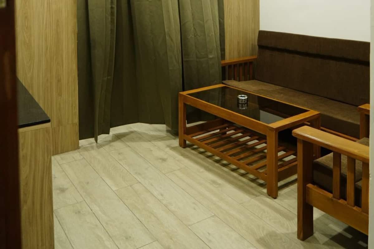 A room with a wooden floor, a ceiling fan, a wooden bench, and a window with curtains.