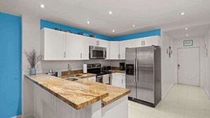 Eine moderne Küche mit weißen Schränken, einer Arbeitsplatte aus Granit, Edelstahlgeräten und einer blauen Akzentwand.