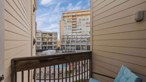 Ein Balkon mit Blick auf ein mehrstöckiges Gebäude, einem Hollerker und einem kleinen Poolbereich.