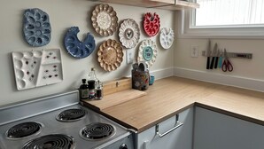 Una cocina con estufa, platos y utensilios.