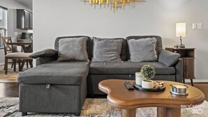 A modern living room with a sectional sofa, a wooden coffee table, and a decorative wall piece. - The Naturehaus - Spacious 4-BR villa with gym/game room in fantastic Bentonville (Bentonville)