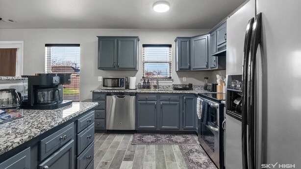 A modern kitchen with grey cabinets, stainless steel appliances, and a granite countertop. - The Naturehaus - Spacious 4-BR villa with gym/game room in fantastic Bentonville (Bentonville)