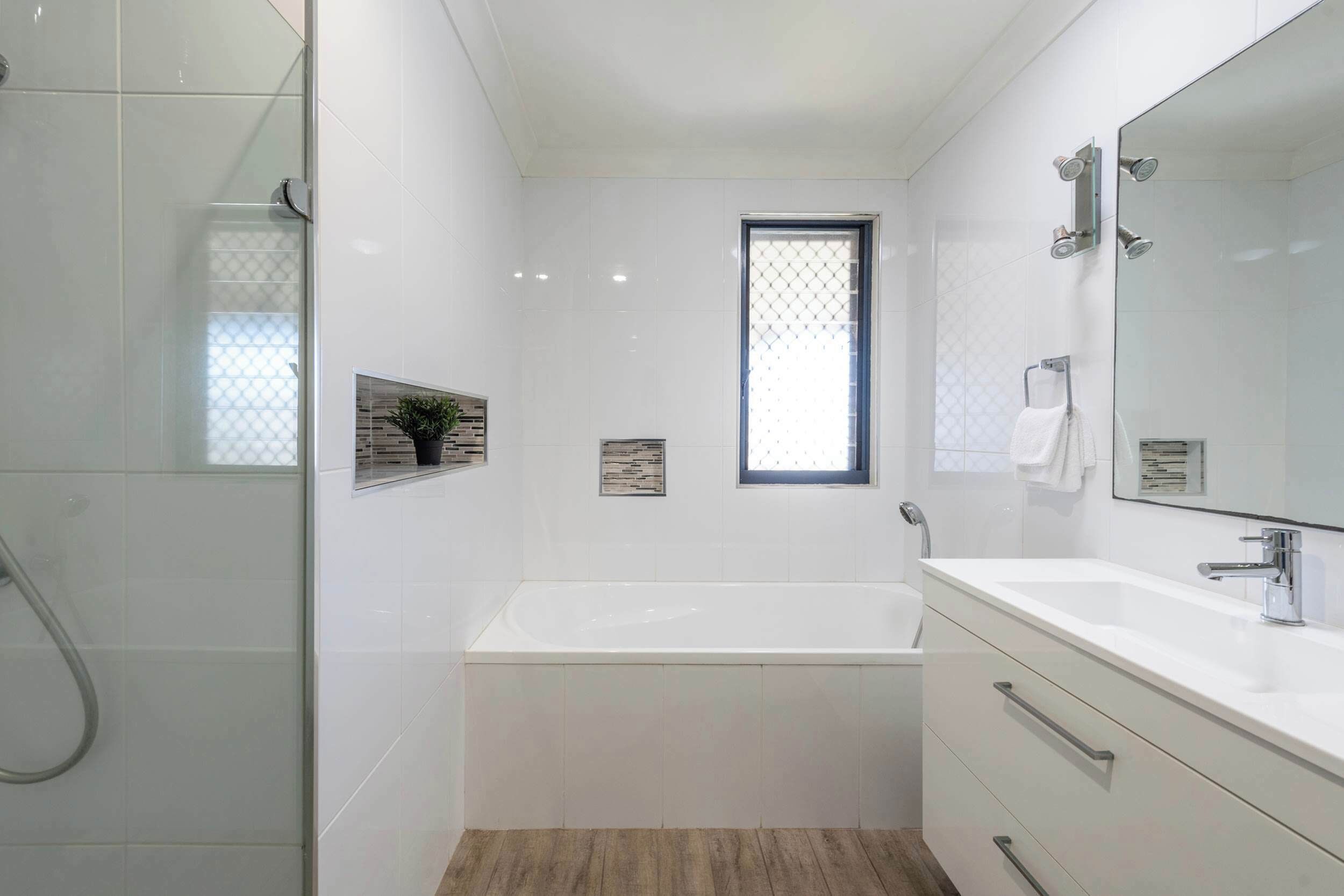 Une salle de bain moderne dotée d’une douche à parois de verre, d’une baignoire sur pieds et d’un grand miroir au-dessus du meuble-lavabo.