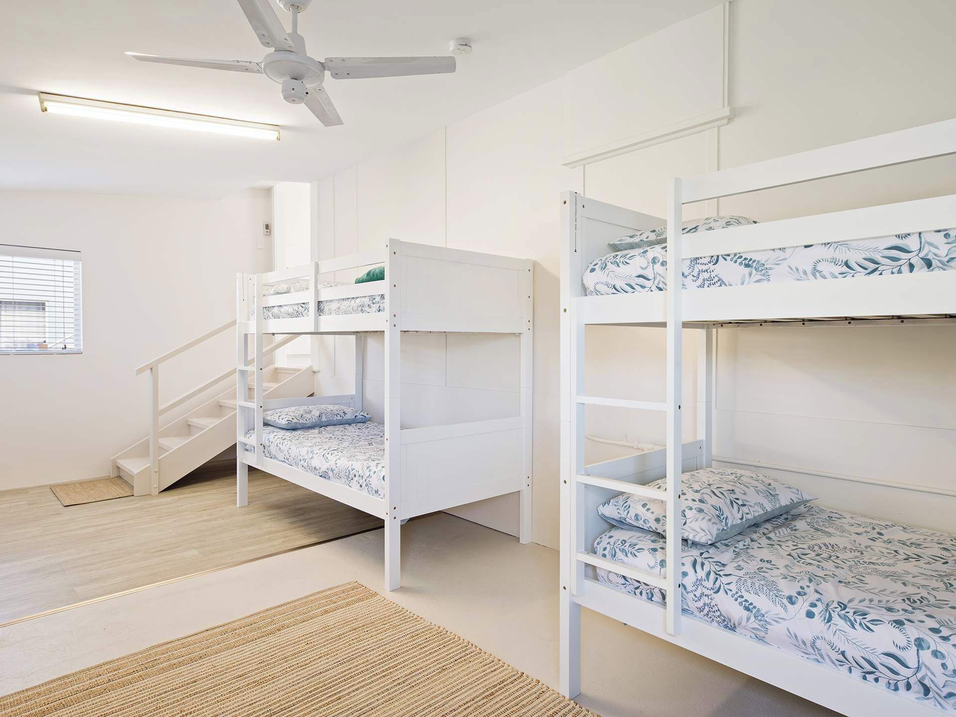 A bunk bed room with a staircase and a ceiling fan.