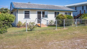 A single-story house with a blue roof, a front porch, and a fenced yard. - Marg's - Oceanstays - Oceanfront (Brooms Head)
