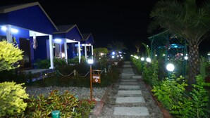 A pathway leading to a blue building with a sign labeled "COTTAGE". - The Tiger Waterfront Resort (Puranpur)