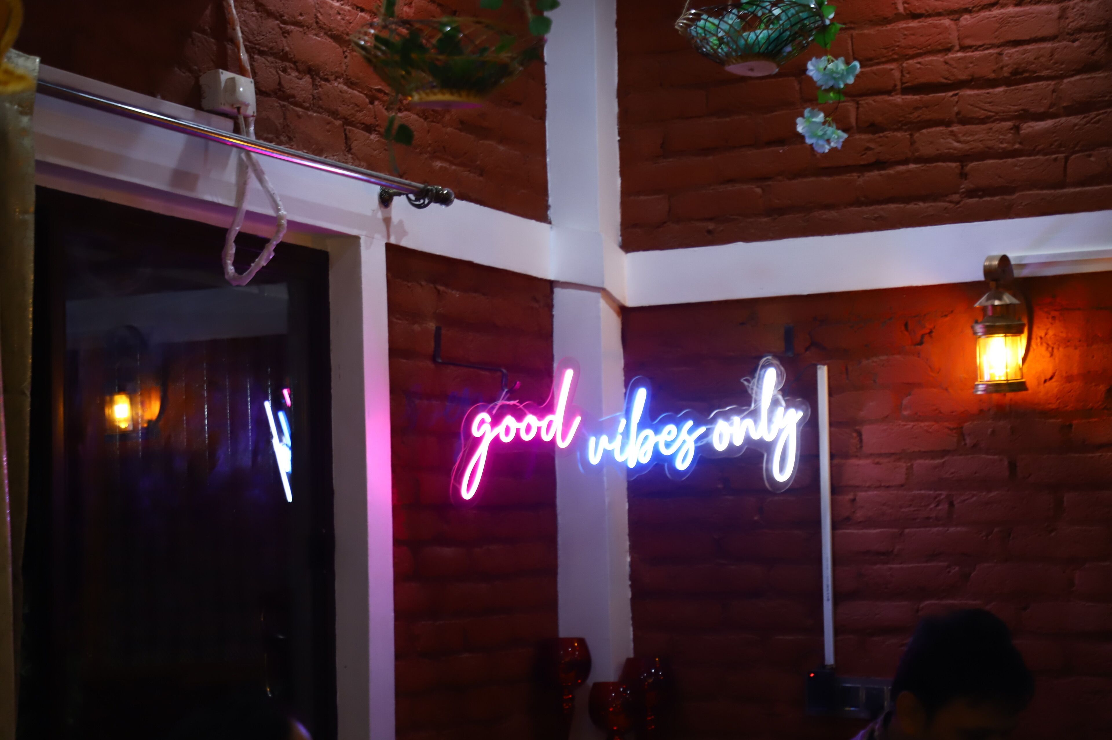 Een kamer met een neonbord waarop staat 'good vibes only' en een bakstenen muur.