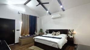 A bedroom with a bed, a ceiling fan, an air conditioner, and a window with curtains. - The Tiger Waterfront Resort (Puranpur)