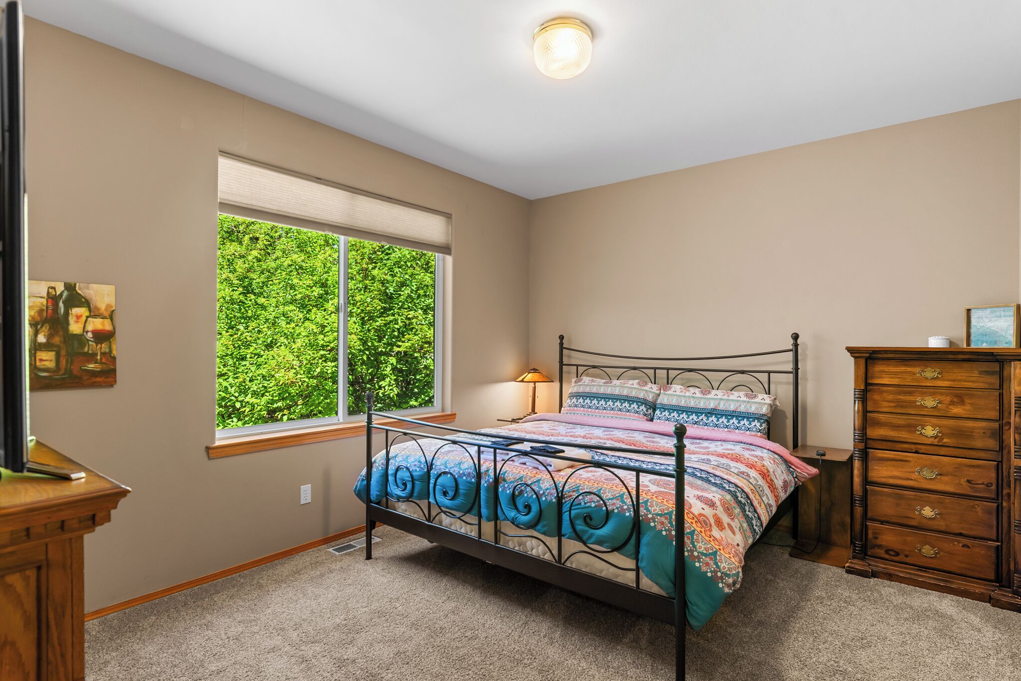 A bedroom with a bed, a dresser, a window with blinds, and a lamp.