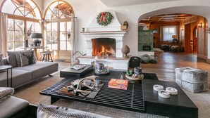 Un salon spacieux avec une cheminée, un canapé, une table basse et un manteau de cheminée décoré d’une guirlande.
