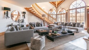 Un salon spacieux avec un escalier, de grandes fenêtres et des meubles modernes.