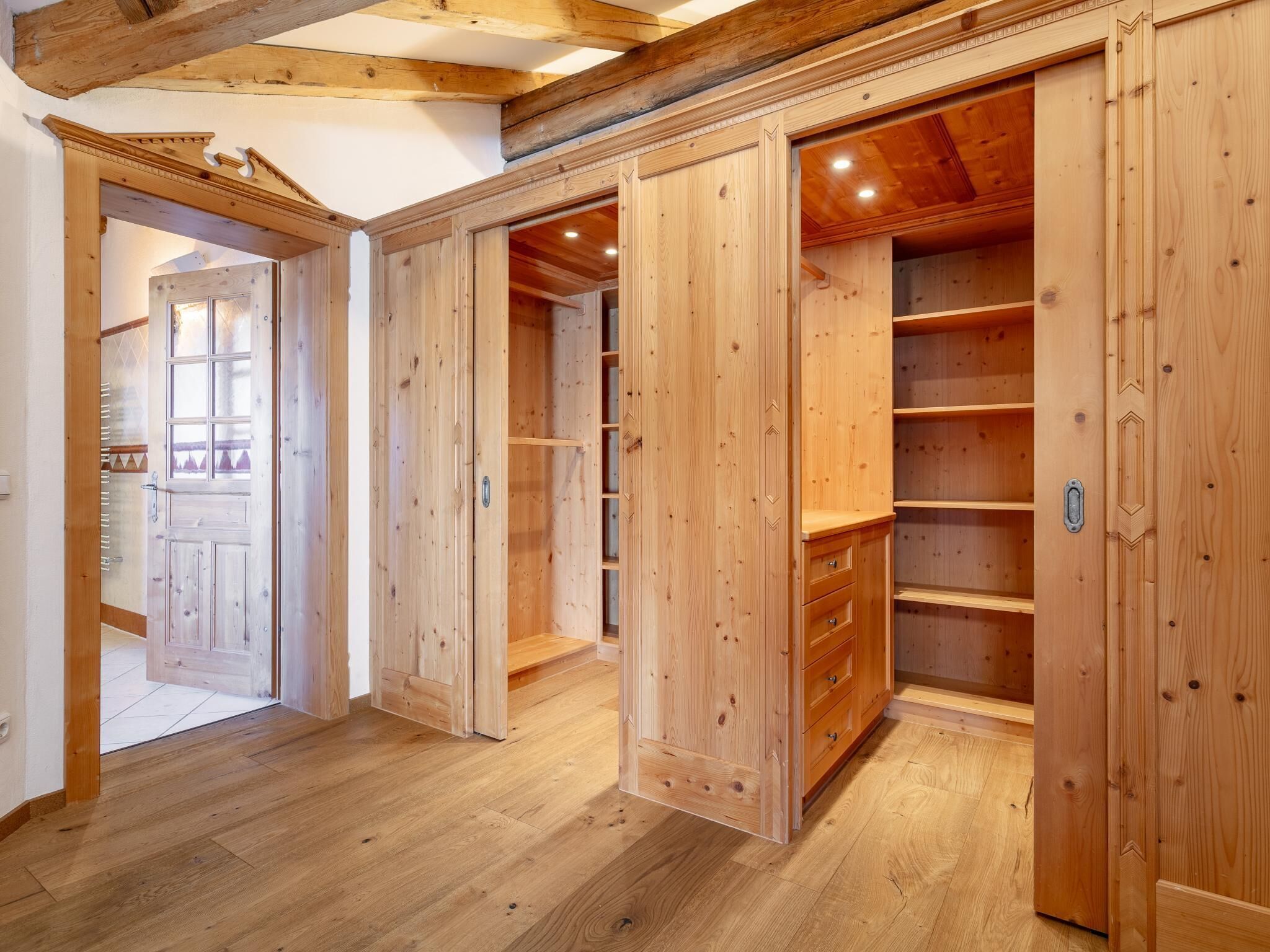 A wooden interior with built-in shelving and a door leading to another room.