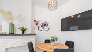 Uma zona de refeições moderna com uma mesa redonda de madeira, cadeiras estofadas a preto, uma planta em vaso e um mapa-múndi na parede.