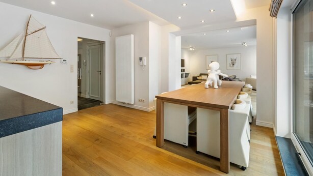 Una cocina moderna con una isla de madera, un adorno con forma de velero y vistas al comedor.