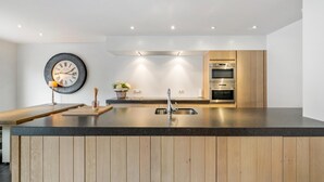 Una cocina moderna con una isla de madera, electrodomésticos de acero inoxidable e iluminación empotrada.