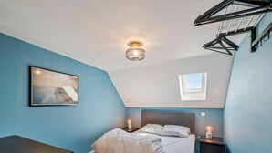A bedroom with a bed, bedside tables, a desk, a ceiling fan, and a skylight. - Spacious Duplex Apartment in Blankenberge (Blankenberge)