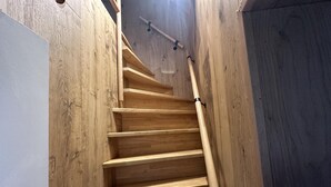 A wooden staircase with a handrail, leading to a landing with a white wall and a wooden floor. - Spacious Duplex Apartment in Blankenberge (Blankenberge)