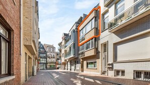 A narrow urban street lined with multi-story buildings, featuring a mix of brick and modern architectural styles. - Spacious Duplex Apartment in Blankenberge (Blankenberge)