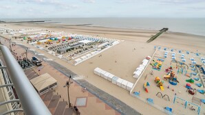Un hotel sulla spiaggia con una vasta area sabbiosa, numerosi ombrelloni e un'area giochi.