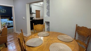 Un coin repas avec une table ronde en bois, quatre chaises et un lustre moderne.