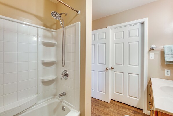 A bathroom with a bathtub, shower, and white tiled walls. - Route 66 Gem! Charming Litchfield Home w/ Yard (Litchfield)
