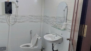 Un baño con inodoro, lavamanos, ducha y espejo.