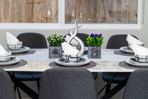 A dining table set with white plates, bowls, and napkins, flanked by decorative vases with flowers. - Pasadena Cottage Retreat Near Rosebowl, DTLA, Old Town Pasadena, PCC, Caltech (Pasadena)