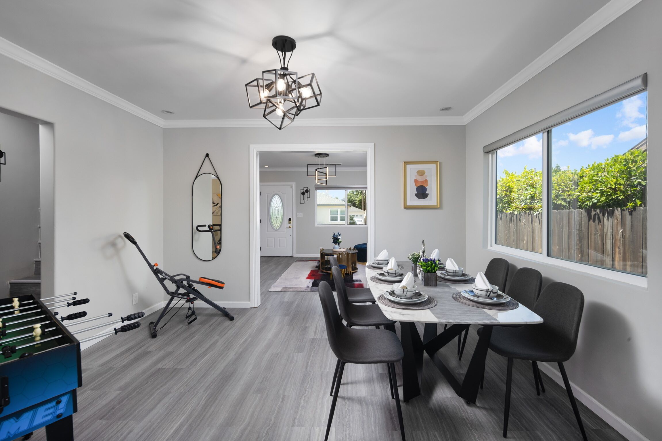 A modern dining area with a table set for four, a foosball table, and a yoga mat.