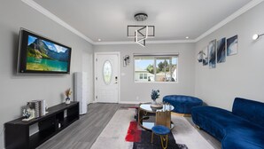 Una sala de estar moderna con un televisor de pantalla plana grande, un sofá azul, una mesa de centro y un tapete decorativo.