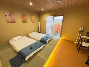 A room with two beds, a sliding door to a balcony, and a massage chair. - SUN WARM HOUSE (Osaka)