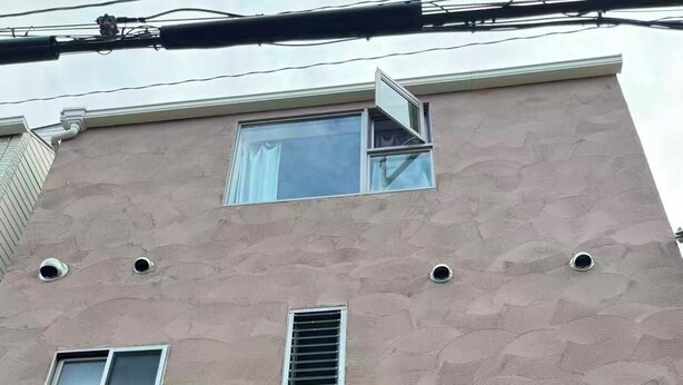 A building facade with a textured surface, a window, a vent, and a logo with a stylized character. - SUN WARM HOUSE (Osaka)