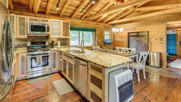 Una cocina moderna con vigas de madera, electrodomésticos de acero inoxidable y encimera de granito.