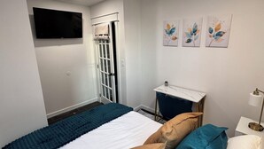 Una camera da letto moderna con un lucernario, un letto con molti cuscini, una scrivania e opere d'arte alle pareti.
