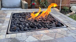 Un braciere con fiamme, circondato da un patio in pietra.