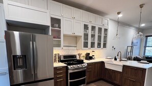 Una cucina moderna con mobili bianchi, elettrodomestici in acciaio inossidabile e pavimento in legno.
