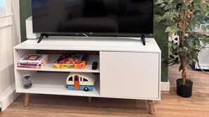 Una televisione a schermo piatto su un'unità bianca con libri e una macchinina.