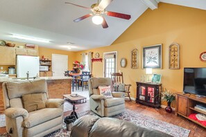 A living room with two beige armchairs, a sofa, a ceiling fan, a television, and a dining area in the background. - Private Yard, 4 Mi to Ole Miss Football (Oxford)