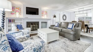 A living room with a fireplace, sofa, coffee table, and a television mounted on the wall. - Close to Connecticut College & Coast Guard Academy (Quaker Hill)